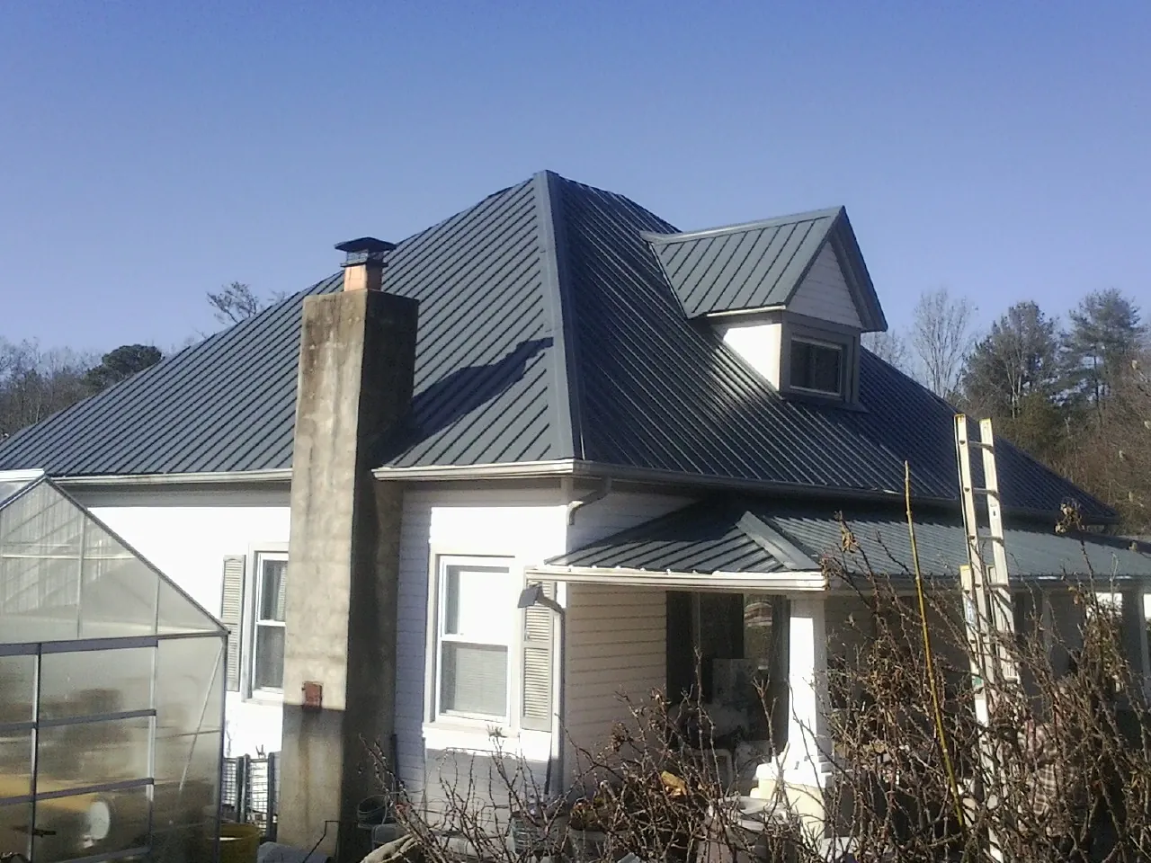 Dark blue standing seam metal roof on a white farmhouse with dormer — Slate & Tile Roof Repair by Roofing Brothers in Covina