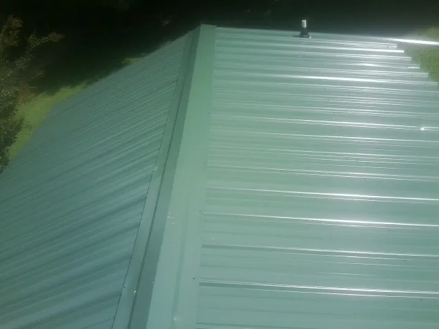 New green metal panels meeting at the ridge of a roof — Flat Roof Repair work by our crew in Covina