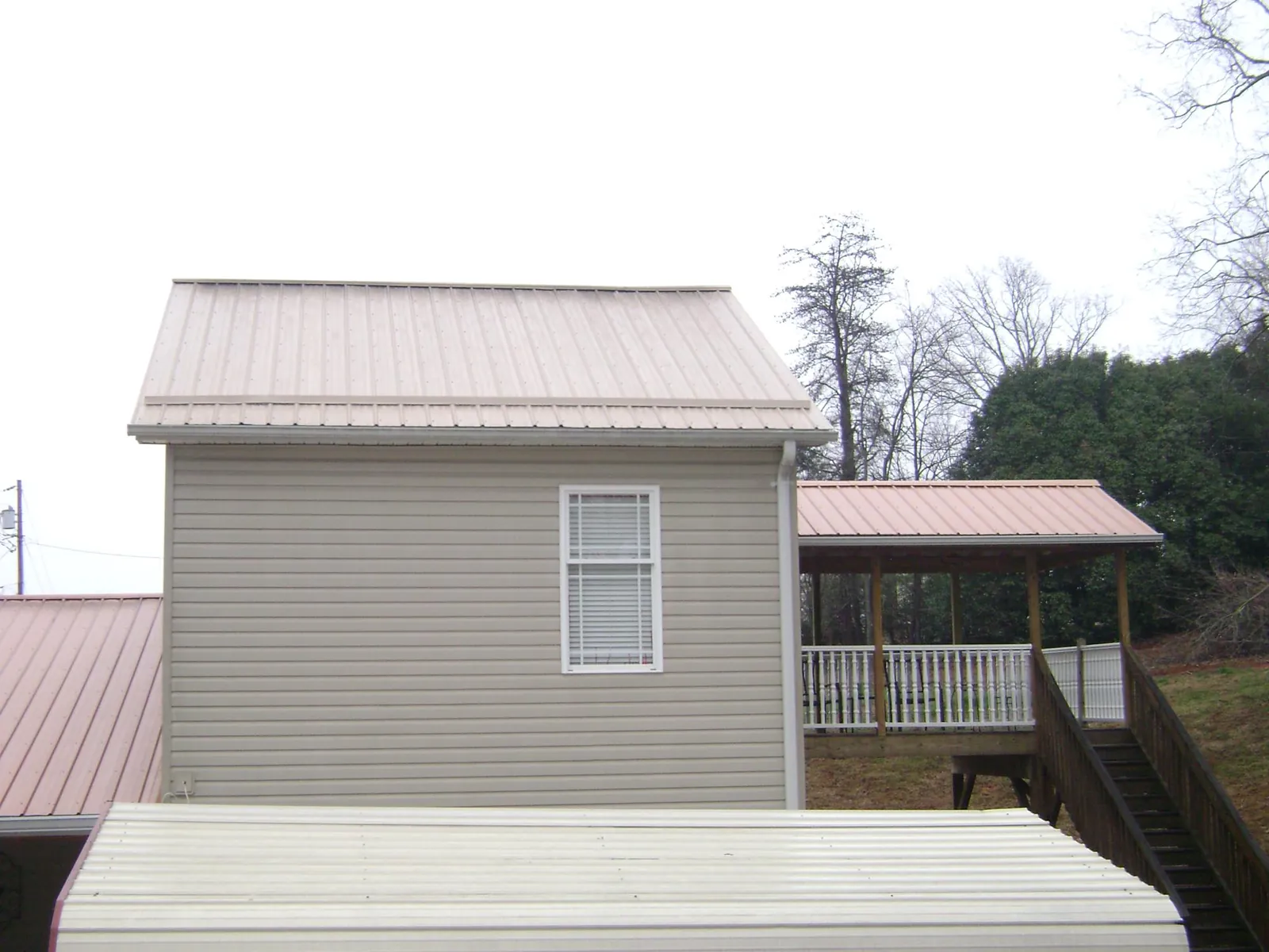 Tan metal roofs on a two story addition and attached porch, from a Roof Replacement job in Covina