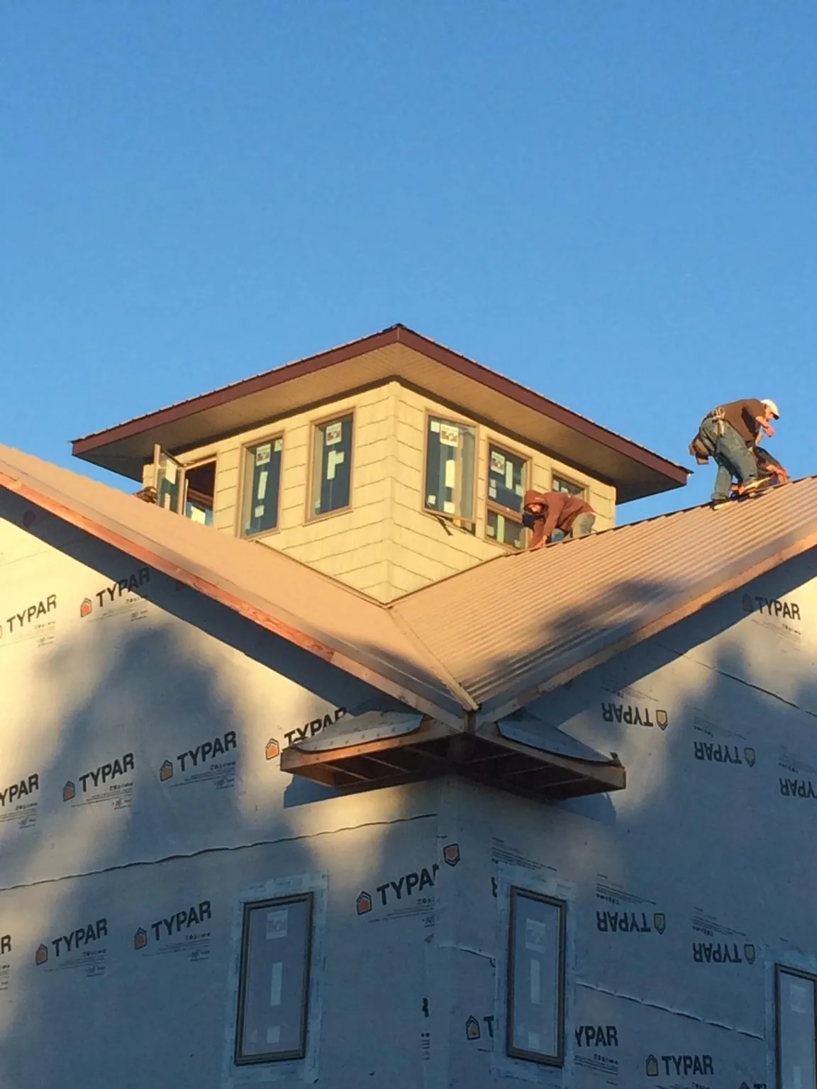 Roofers working around a rooftop cupola on a new metal roof at sunset — Roof Waterproofing in Covina by Roofing Brothers